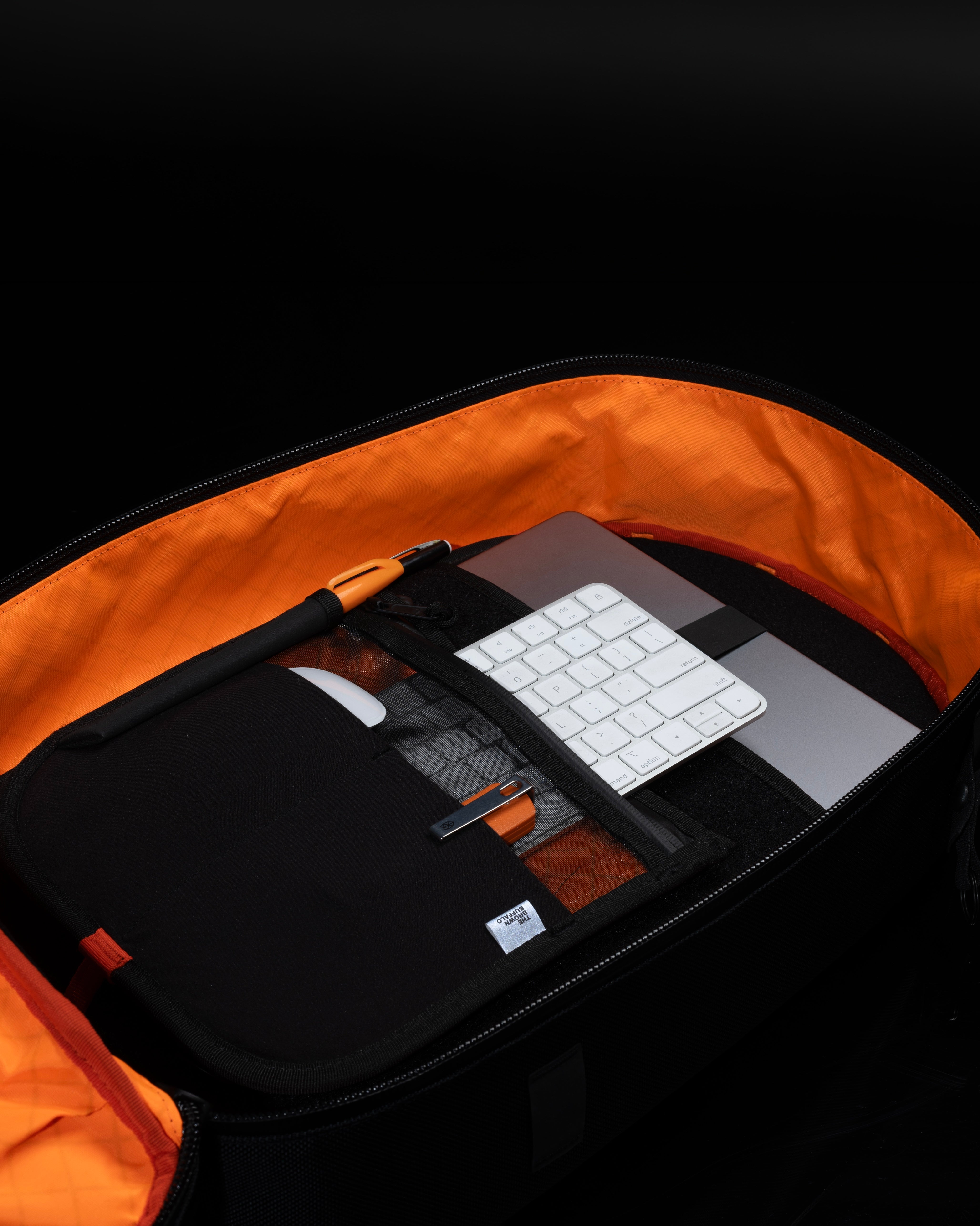 Open backpack with laptop and keyboard compartments on a black background